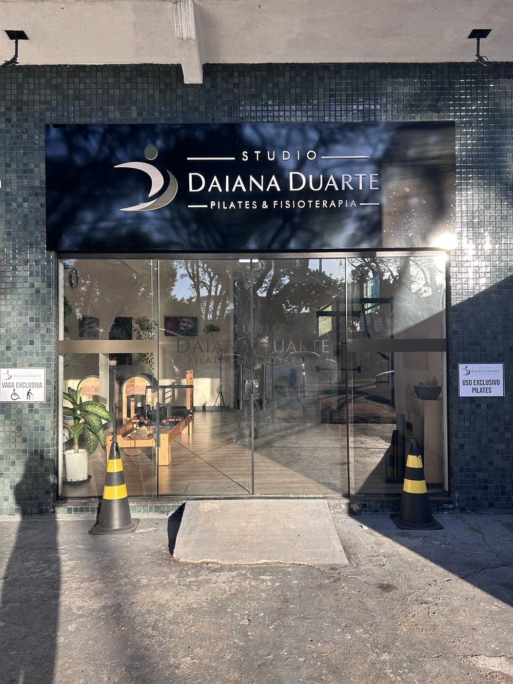 Fachada e entrada do Studio Daiana Duarte, com placa de vaga exclusiva para pessoas com deficiência