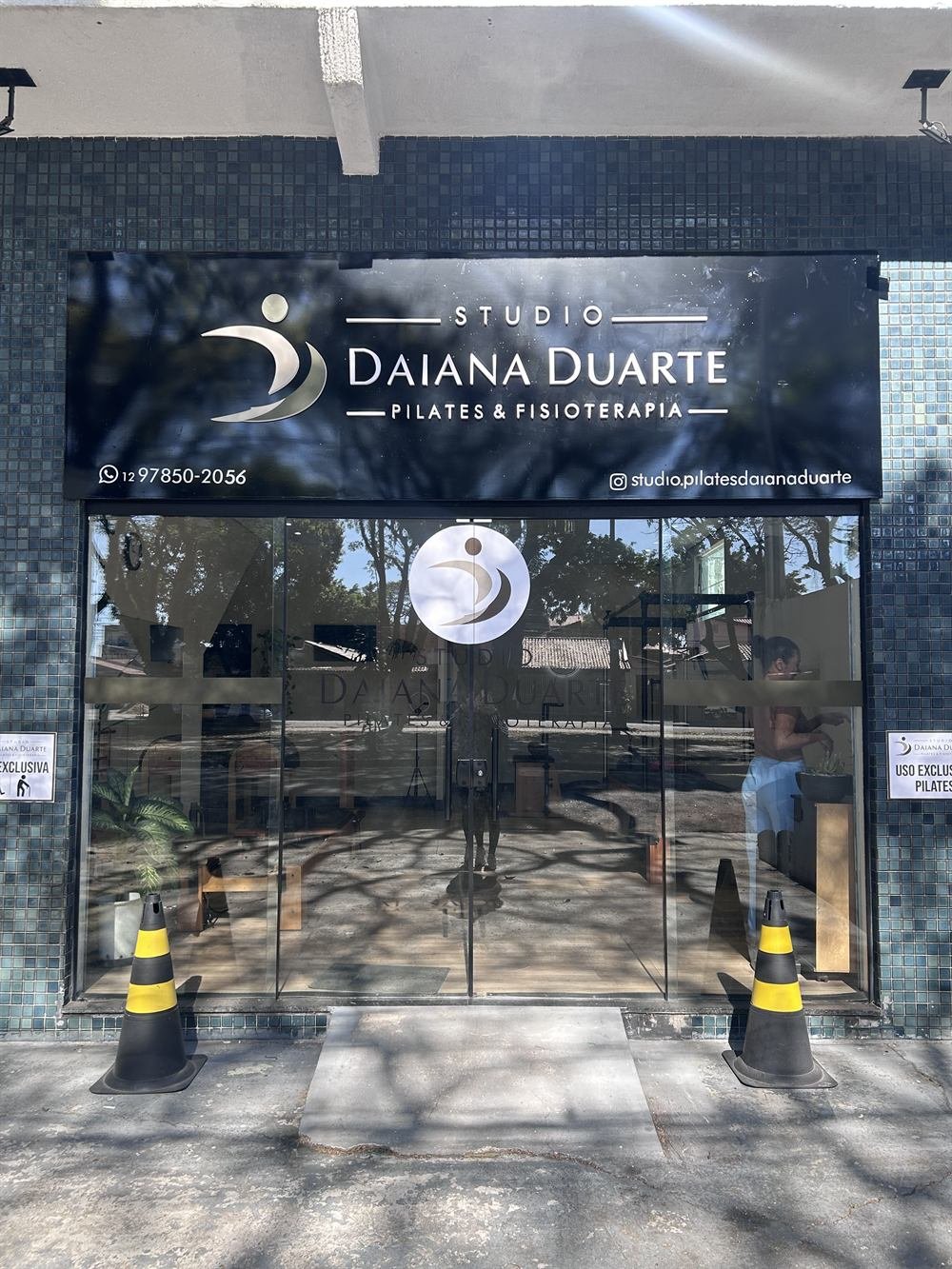 Fachada do Studio Daiana Duarte com o letreiro, o telefone e o Instagram do estúdio